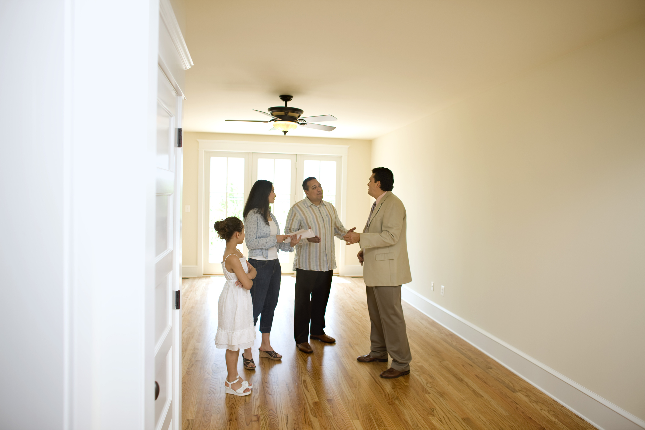 Family of three standing with realtor in new home, empty no furniture